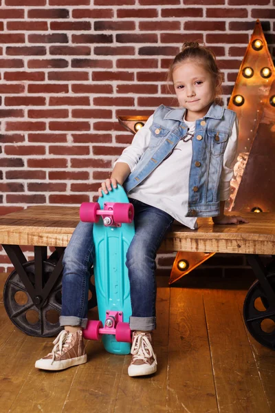 Стильная девочка с голубым скейтбордом дома — стоковое фото