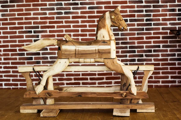 Old rocking horse on a brick wall background
