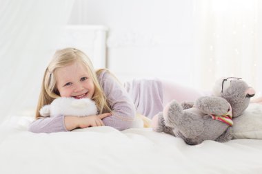 Oyuncak ayı ile yatakta yatan kız çocuk