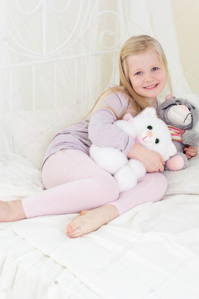 Child girl in the bed with her toys