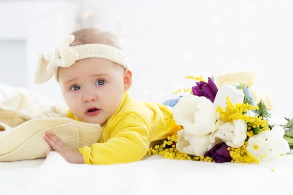 Baby girl in bed with spring flowers — Stock Photo, Image