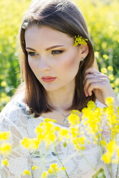 สาวสวยในสนามกับดอกไม้สีเหลือง — ภาพถ่ายสต็อก