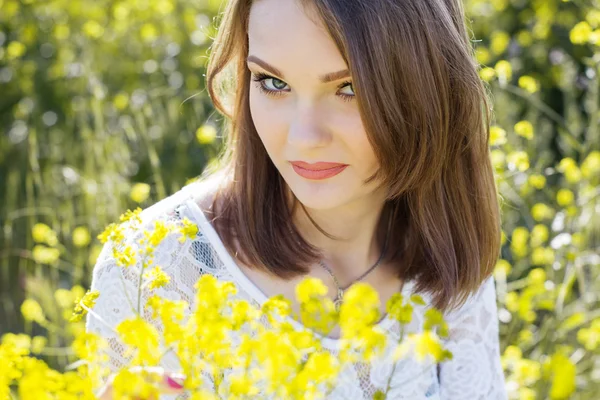 Menina bonita no campo com flores — Fotografia de Stock