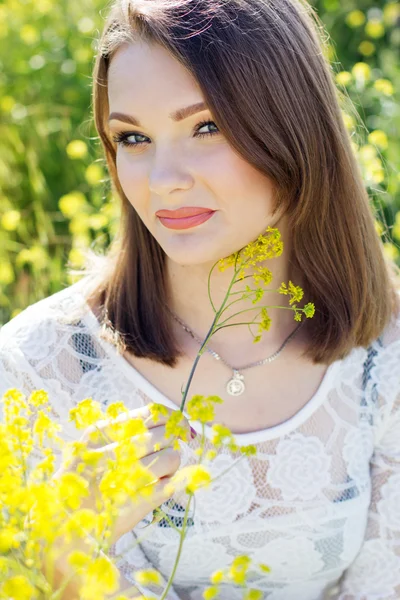 Mooie vrouw in veld met bloemen — Stockfoto