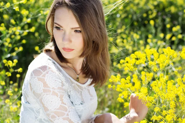 Vacker flicka i fält med gula blommor — Stockfoto