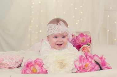 Kız bebek pembe çiçekler ile yatakta yatarken