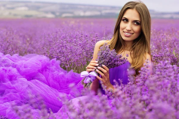 Mooi meisje zit in Lavendel veld — Stockfoto