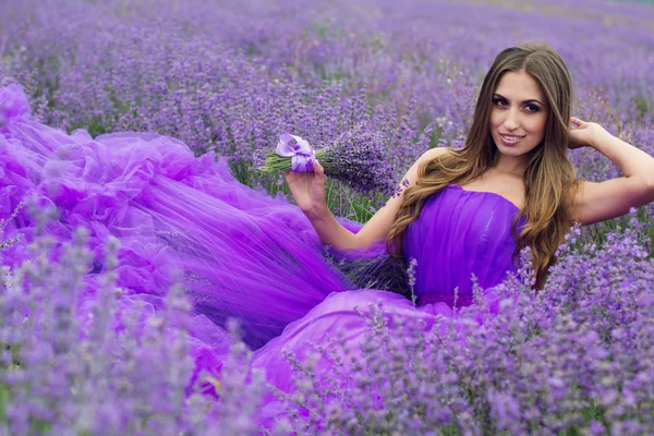 Lächelndes hübsches Mädchen sitzt im Lavendelfeld — Stockfoto