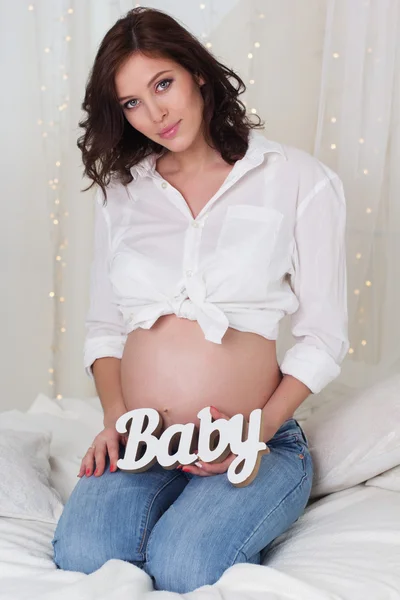 Chica bonita embarazada con letras de madera bebé — Foto de Stock