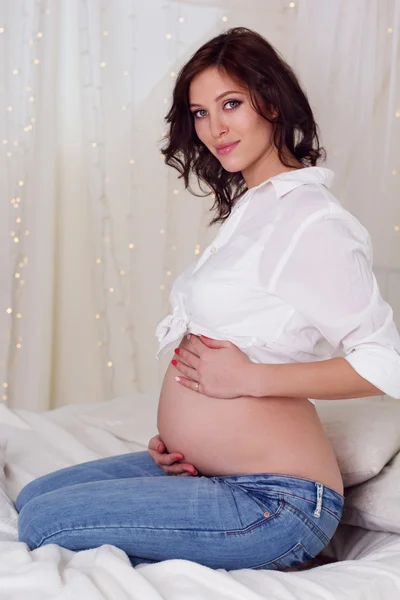 Yatağın üstüne oturan güzel hamile kız — Stok fotoğraf