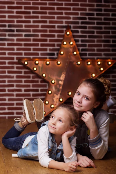 Zwei Mädchen liegen zu Hause vor Ziegelmauer — Stockfoto