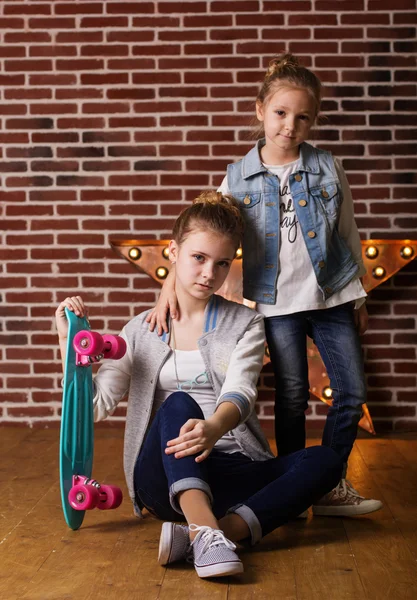 Two sisters with skateboard in studio — Stock Photo, Image