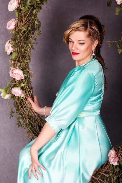 Adorable woman is wearing fashion dress sitting on swing — Stock Photo, Image