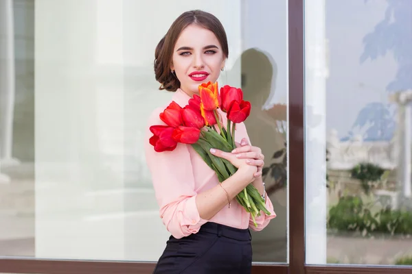 Hübsches Mädchen mit roten Tulpen — Stockfoto