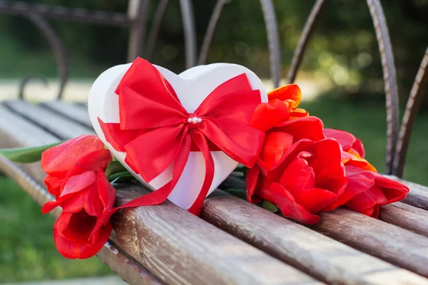 Red tulip flowers and gift box on wooden table — Stock Photo, Image