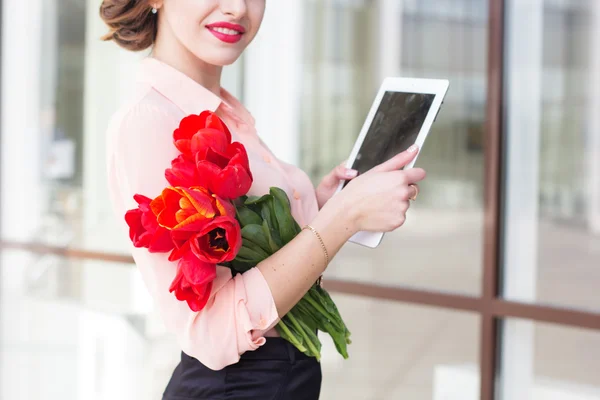 Belle fille avec dispositif électronique et fleurs rouges — Photo