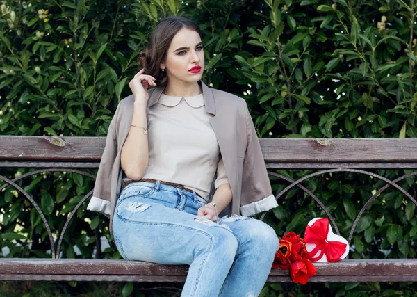Söt flicka med tulpaner sitta på bänken — Stockfoto