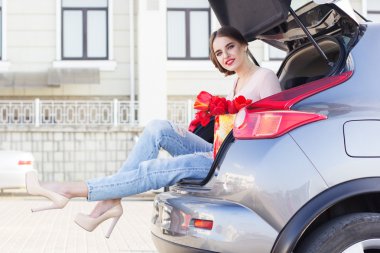 Kız araba gövde kırmızı çiçekli oturuyor