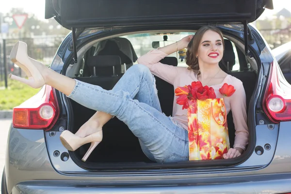 Meisje in de auto kofferbak met pakket van bloemen — Stockfoto