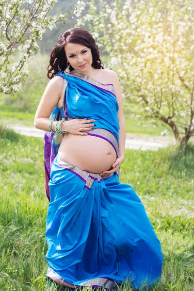 Беременная девушка носит сари на природе — стоковое фото
