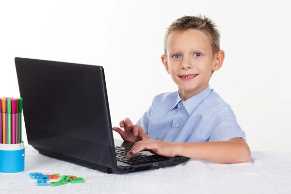 Menino feliz está fazendo lição de casa no laptop — Fotografia de Stock