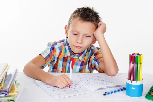 Tired school boy with sad face is doing lessons Stock Picture