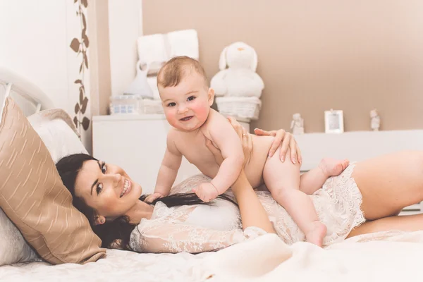 Mãe muito feliz e filho pequeno estão deitados na cama — Fotografia de Stock