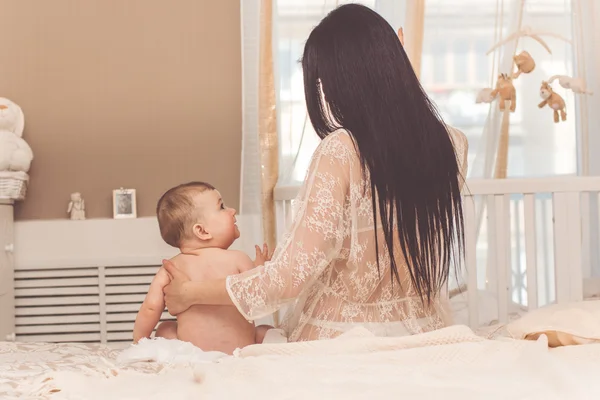 Mãe muito feliz e pequeno filho estão sentados na cama — Fotografia de Stock