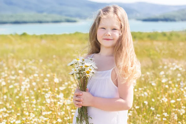 Cute smiling child girl at camomile field — Stock Photo, Image