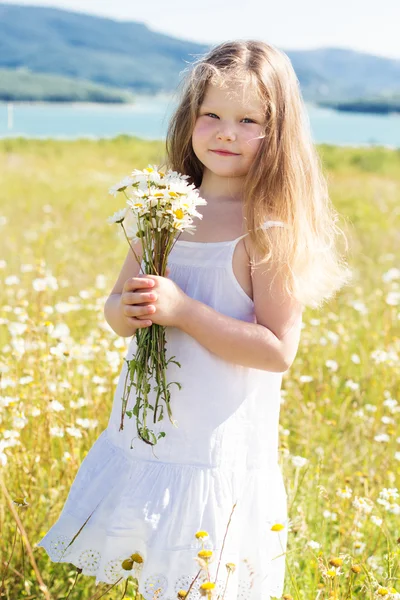 Roztomilá dívka usmívající se dítě na poli heřmánek — Stock fotografie