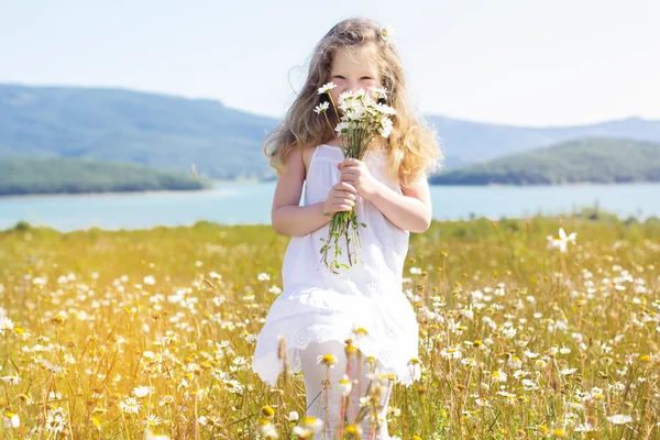 Cute smiling child girl with camomile flowers — Stock Photo, Image