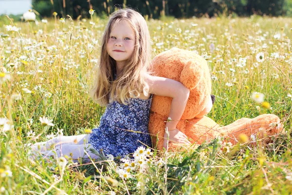 Niña bonita en el campo de manzanilla con oso de peluche —  Fotos de Stock