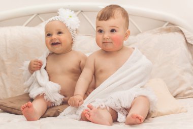 İki sevimli bebek yatakta oturuyor