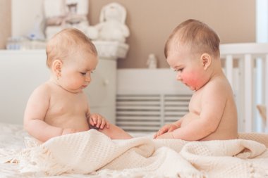 İki çıplak bebek erkek ve kız yatakta oynuyorlar