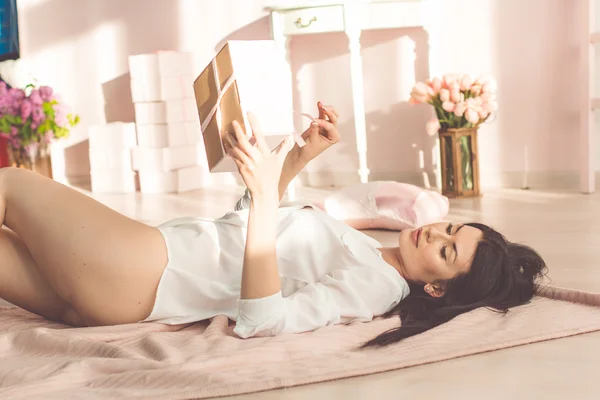 Menina sexy está deitada no chão com caixa de presente rosa — Fotografia de Stock