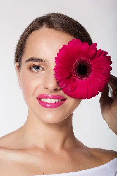 Söt tjej med perfekt hud håller gerbera blomma — Stockfoto