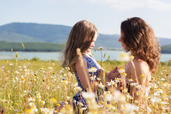 Mom with baby girl are sitting in chamomile field — Stock Photo, Image