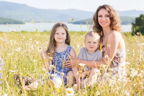 Familie: moeder, meisje en jongen op kamille gebied — Stockfoto