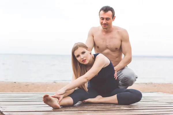 Man and pregnant girl are doing yoga at sea coast — Stock Photo, Image