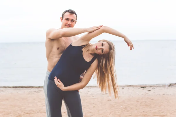 Man and pregnant woman are doing yoga on the beach — Stock Photo, Image