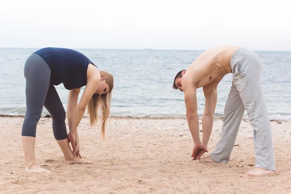 Man and pregnant woman are doing yoga on the beach — Stock Photo, Image