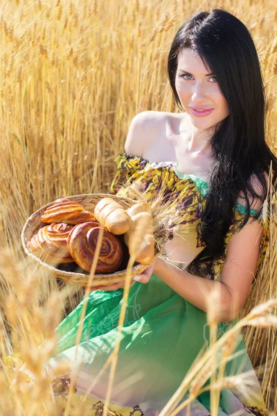 Chica en el campo de centeno con cesta de bollos y rollos —  Fotos de Stock