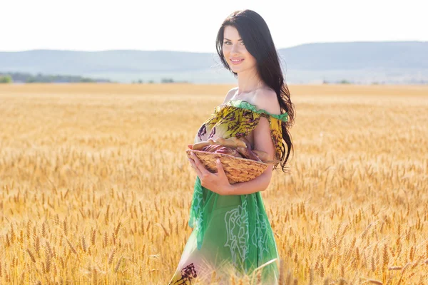 Lány rozs mezőben kosár zsemlét és tekercsek — Stock Fotó