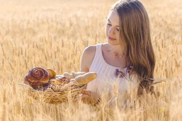 Jeune fille dans le champ de seigle avec panier de petits pains — Photo
