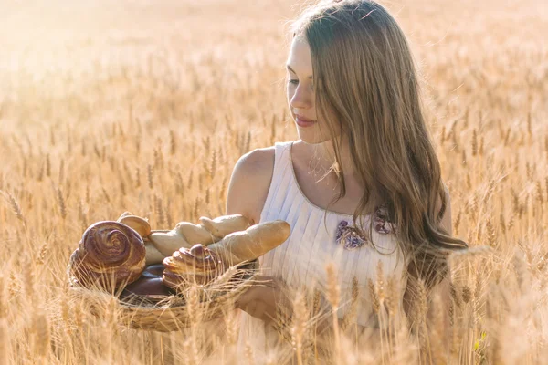 Jeune fille dans le champ de seigle avec panier de petits pains — Photo