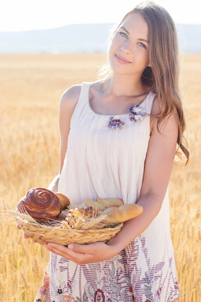 Jeune fille dans le champ de seigle avec panier de petits pains — Photo