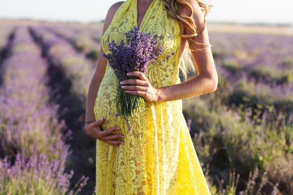 Vientre de la mujer embarazada en un campo de lavanda — Foto de Stock