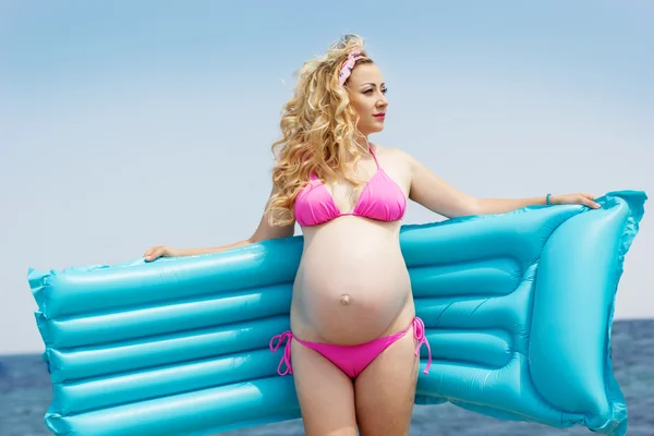 Pregnant woman with mattress on the beach — Stock Photo, Image