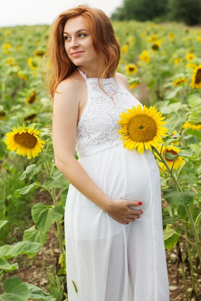Беременная девушка в поле с подсолнухами — стоковое фото