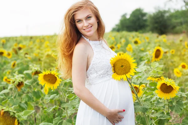 Schwangere auf dem Feld mit Sonnenblumen — Stockfoto